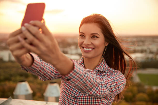 istock Joyful woman taking selfie on smartphone on roof 1301309157
