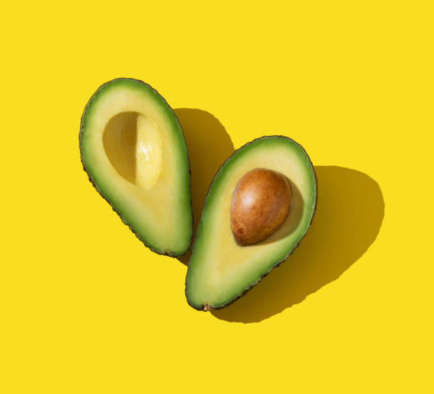 istock Avocado halves with trendy lighting and hard shadow on yellow background 1301313725