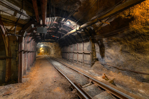 Tunnel of the mining of an underground mine. Lots of pipelines on the ceiling and rail track for trolleys Tunnel of the mining of an underground mine. Lots of pipelines on the ceiling and rail track for trolleys. gold mine photos stock pictures, royalty-free photos & images