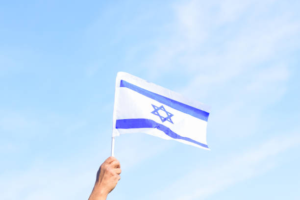 istock Israeli flag, man hand, blue sky, nature background.Copy space for text 1301326709