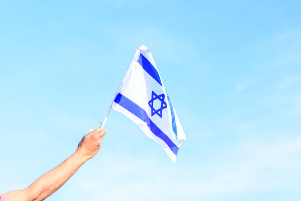istock Israeli flag, man hand, blue sky 1301326735