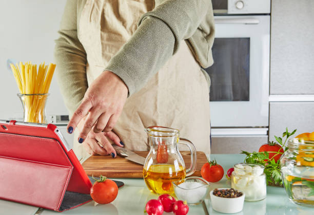 istock Woman use finger slide on tablet screen cooking according the tutorial of online virtual master class, And looking on the digital recipe, using touchscreen tablet while cooking healthy meal on the kitchen at home 1301331382