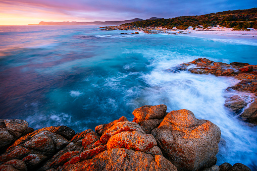 A sunrise seascape under a stormy sky on the east coast of Tasmania in Freycinet National Park.