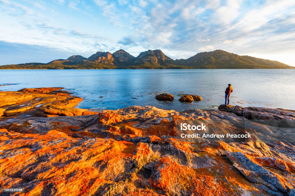 A woman enjoys a sunset view of The Hazards from Coles Bay The Hazards are a great walking destination within Freycinet National Park. Tasmania Stock Photo