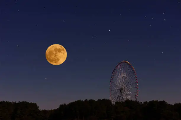 Full moon rising over the Ferris Wheel with copy space.