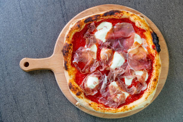 istock Directly above pizza on round board with melted mozzarella cheese and prosciutto 1301340626