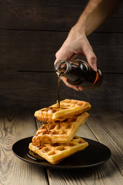 wiener waffeln werden mit sirup aus einer flasche gegossen. - waffle syrup pouring breakfast stock-fotos und bilder