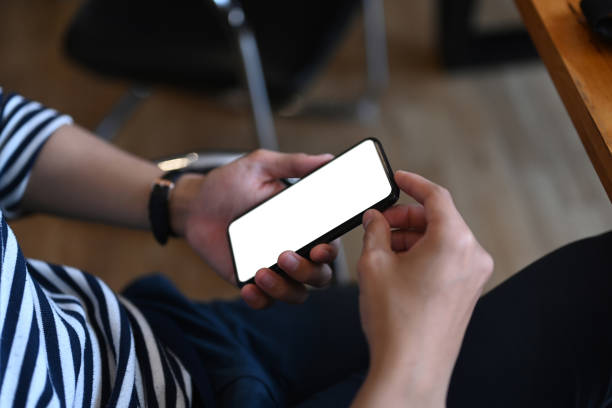 istock Close up view of young man holding mock up mobile phone with blank screen while sitting at his workplace. 1301340815