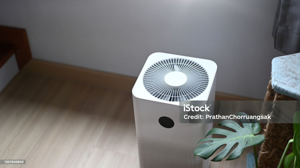 Air purifier in comfortable living room with house plant on the wooden floor. Air Purifier Stock Photo