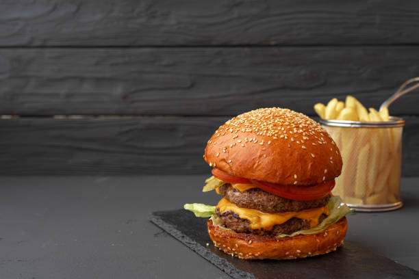 istock Fresh burger and fries on black wooden background 1301340954