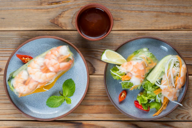 istock Two Vietnamese spring rolls with shrimps and lime on two plates with sauce. 1301341693