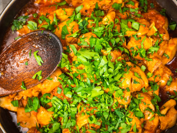 Chicken curry sprinkled with chopped parsley in a bowl on a wooden brown table, close up