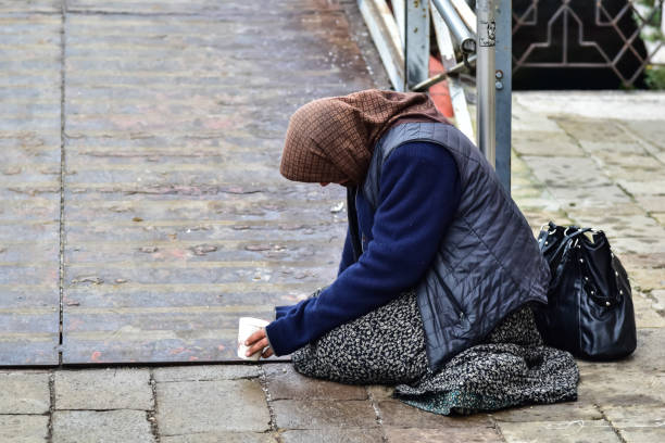 Beggar woman begging for money Milan, Italy - April  27, 2019: Beggar woman begging for money passersby kneeling on the ground alms stock pictures, royalty-free photos & images