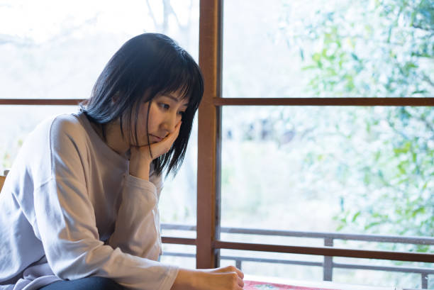 窓の中のアジア人女性の肖像 - ストレス ストックフォトと画像