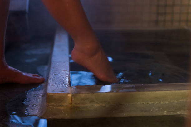 An Asian woman takes a bath in a Japanese hot spring.Dipping her toes into the hot spring.Smooth, mineral-rich hot spring water.feels good. Relaxation. Healing. Natural hot spring.