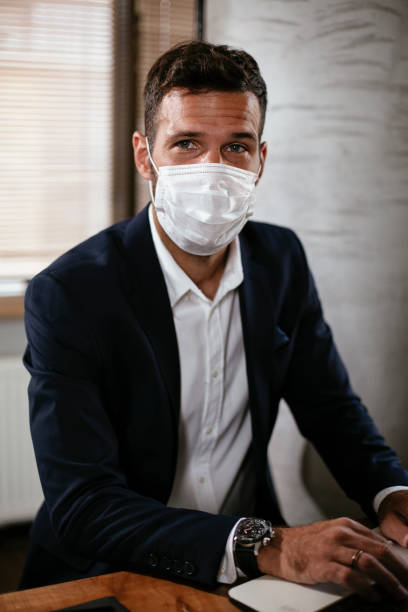 istock Young businessman with a mask working in his office on laptop. 1301348775