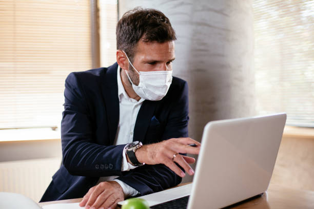 istock Young businessman with a mask working in his office on laptop. 1301348855