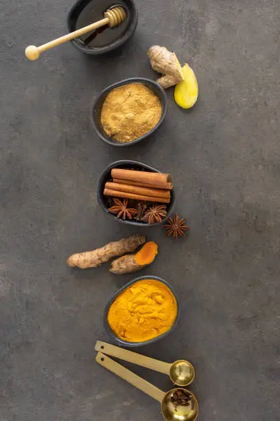 Ingredients  for making Ayurvedic beverage Golden Milk ginger, turmeric, anise, clove and cinnamon spices on black background.