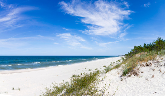 Footpath through sand dunes overlooking the sea with a colorful sailing ship