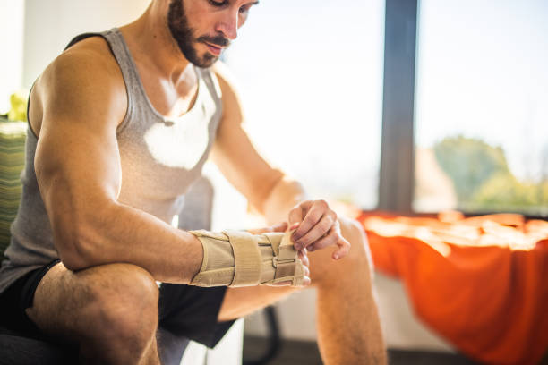 istock Young man putting on wrist brace before exercising 1301353726