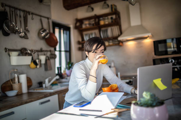 istock Woman using laptop in the kitchen 1301353903