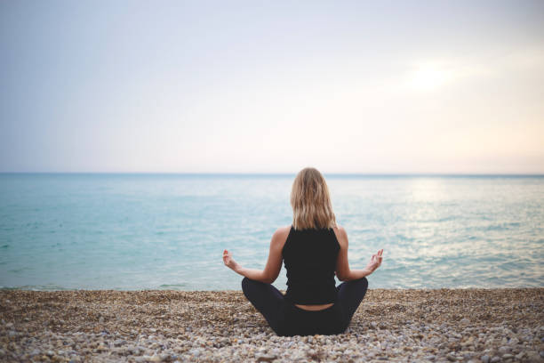 istock woman doing yoga at sunset on the beach 1301354687