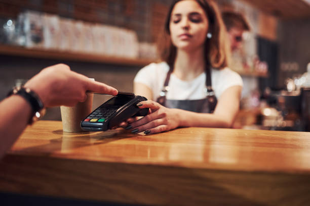istock Paying by using digital system. Young female cafe worker indoors. Conception of business and service 1301356756