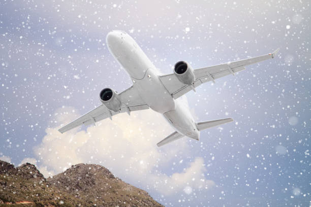 istock white passenger plane flies through falling snow against the mountains with white clouds on blue sky background in autumn.  Landscape with airplane, mountains and blue sky with white clouds in summer 1301359842