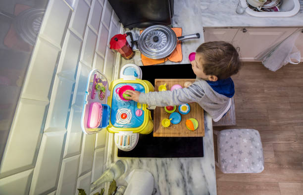 istock Baby boy playing with toy kitchen over real kitchen countertop 1301360071