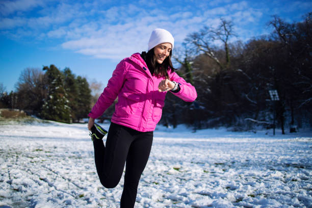 Sportswoman in winter stretching and warming up her body before training on snow.