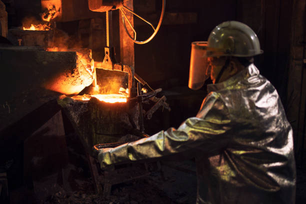 istock Founder in protective suit working with hot liquid steel in foundry. 1301361217