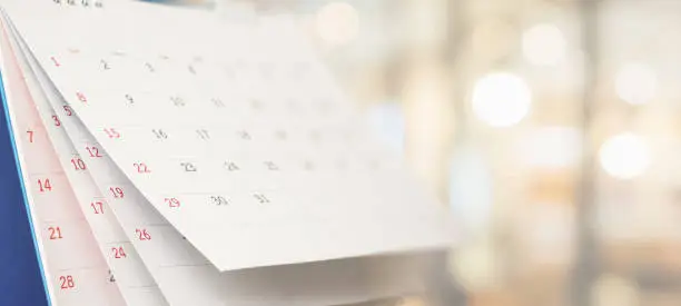 Close up white paper desk calendar with blurred bokeh background appointment and business meeting concept