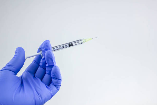 istock Hand in blue glove holding a plastic syringe 1301364996
