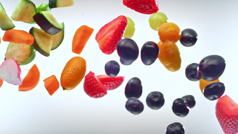 SLO MO LD A mix of cut fruits and vegetables colliding in the air