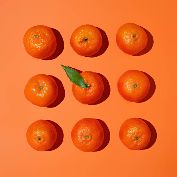 istock Fresh orange citrus with leaf and shadows forming geometrical square shape on pastel orange background 1301369140