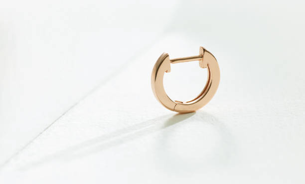 istock gold earring on a white paper background 1301371228