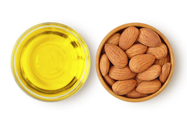 almond oil in glass bowl and almonds in wooden bowl on white background - diabetes superfoods imagens e fotografias de stock