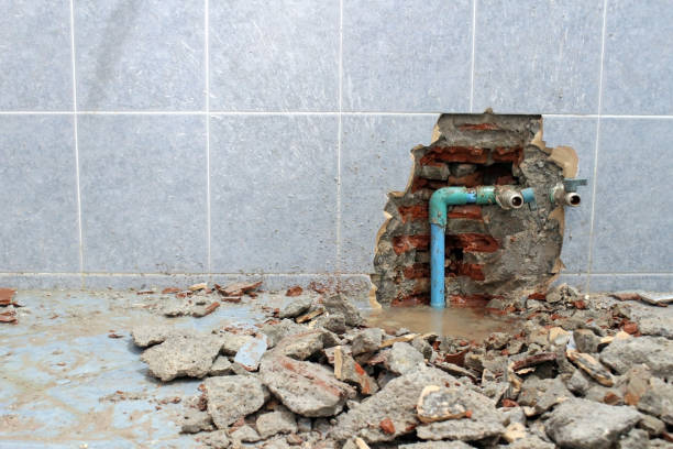Floor and wall tiles broken revealing leaky water pipes in a residential building Plumbing problems. A wall of a bathroom is opened to find a leak from a pipe leaving rubble on the floor. faucet leaking pipe water stock pictures, royalty-free photos & images