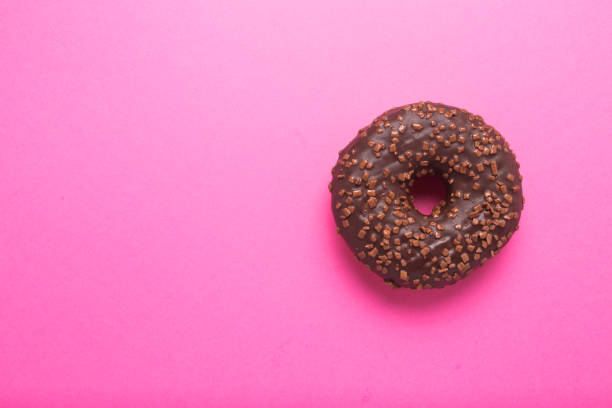 istock Chocolate donut on a pink background close-up 1301373462