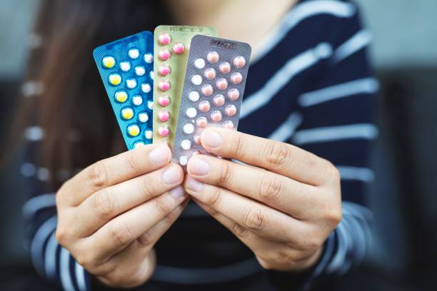 Doubtful confused young woman feels unsure taking medicine contraceptive, depressed unhealthy girl holding pack of contraceptive pills. stock photo