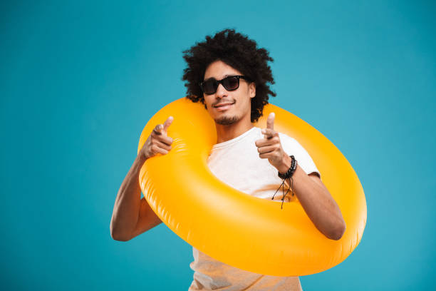 istock Happy handsome young african curly man holding rubber ring pointing to you. 1301377604