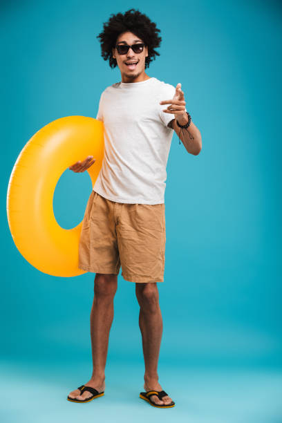 istock Happy handsome young african curly man holding rubber ring pointing to you. 1301377959