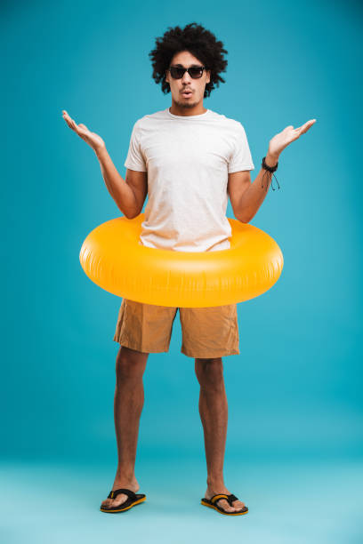 istock Shocked young african curly man holding rubber ring. 1301379176