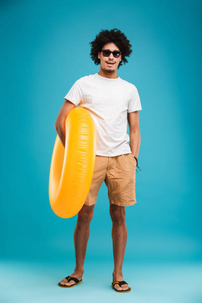 istock Handsome young african curly man holding rubber ring. 1301379664