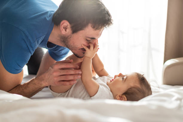Father and baby playing on bed