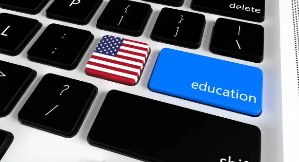 Photo of Computer keyboard with word Education and American Flag, selected focus on enter button.