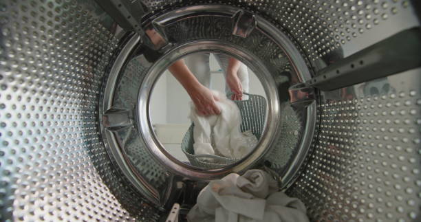istock A woman puts white laundry in the washing machine 1301381057