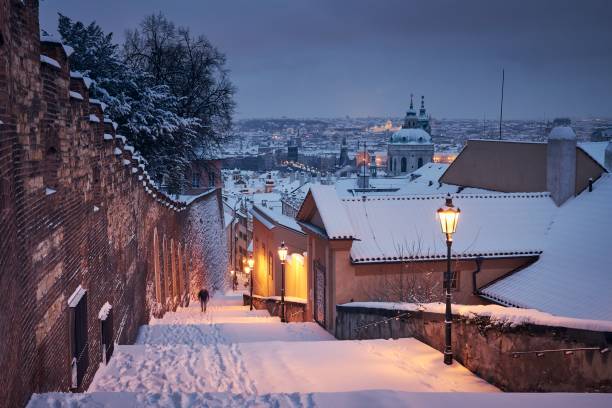 Cityscape of Prague in winter Cityscape of Prague in winter.  Lonely man (in blurred motion) walking on staircase against Lesser Town early morning. st nicholas church prague stock pictures, royalty-free photos & images