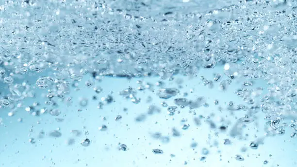 Detail of waving water with bubbles, closeup. Abstract aqua background.