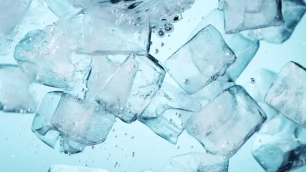 Detail of whirling water with ice cubes, closeup. Abstract aqua background.